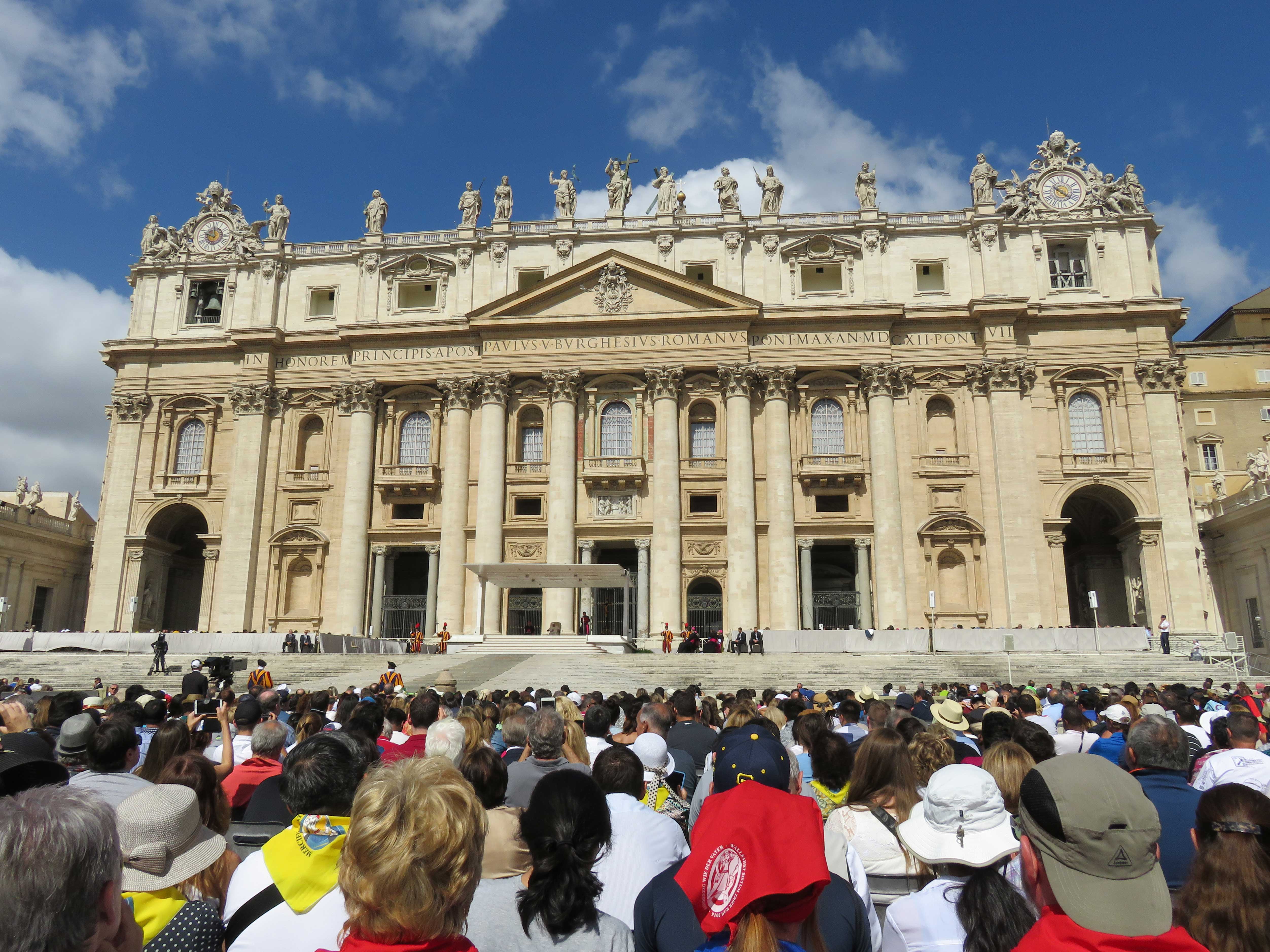 Vorne viele Gläubige, hinten Papst Franzikus