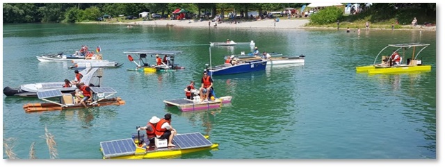 Das Bild zeigt verschiedene von Schülerinnen und Schülern selbst gebaute Solar-Boote auf einem See.