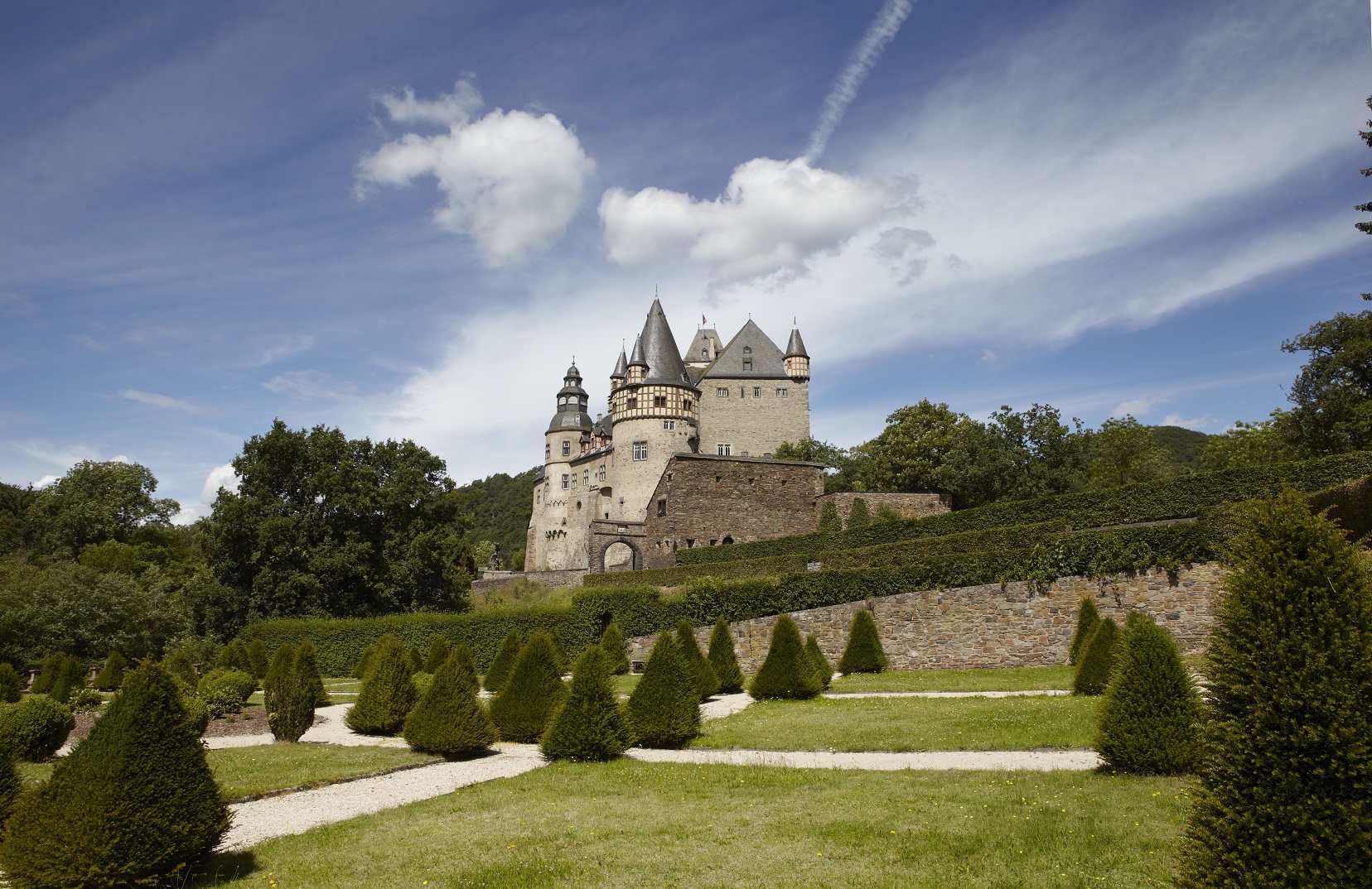 Ein Schloss umgeben von Bäumen und mit einem Garten im Vordergrund