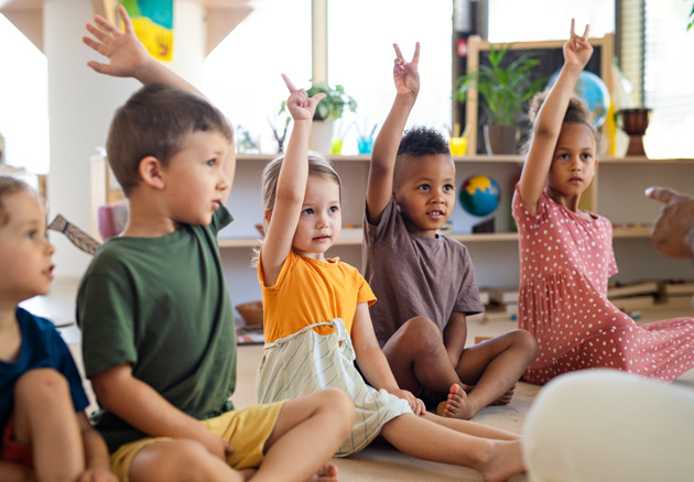 Kinder im Kindergarten heben die Hände