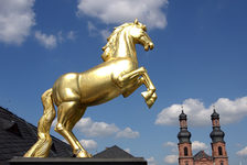 Bildergalerie Golden-Ross-Kaserne Goldenes Ross des Landesmuseums, Türme von St. Peter im Hintergrund Elegant steht es auf den beiden Hinterbeinen und erweckt den Eindruck, als setze es zum Sprung an: Das goldene Ross auf dem Eingangsportal des Gebäudes, das im seinen Namen verdankt. Im Hintergrund ragen die beiden Türme der Kirche St. Peter.