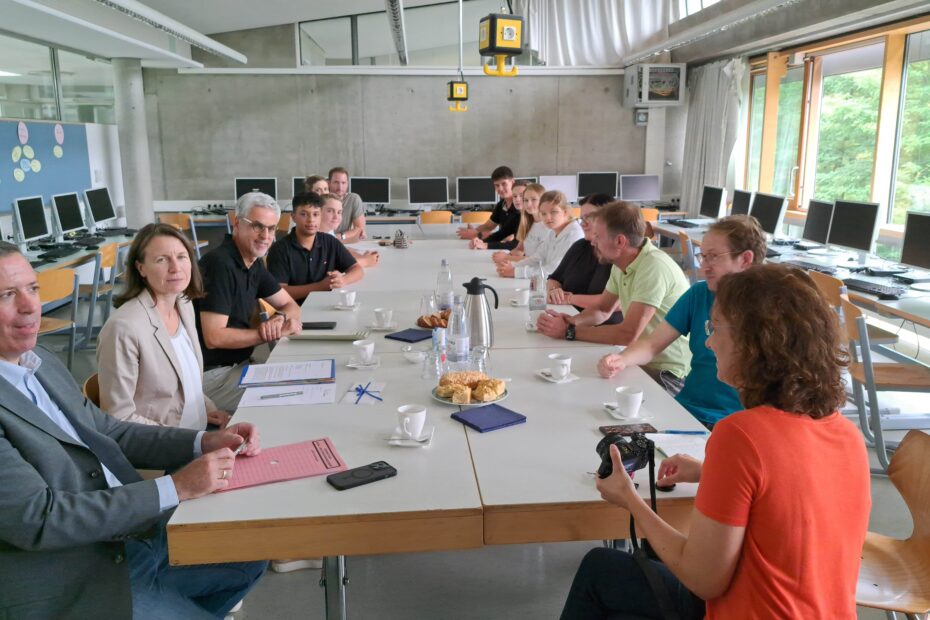 Die Landrätin Cornelia Weigand sitzt mit Vertretern der Schule an einem Tisch.