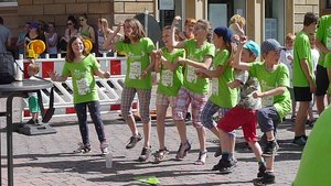 Kinder in grünen T-Shirts hüpfen gemeinsam hoch