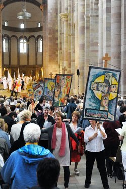 Frauen im Mittelgang des Speyerer Domes mit bunten Fahnen.