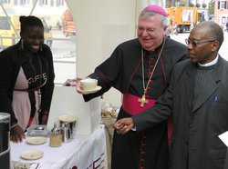 Weihbischof Georgens und der ruandische Bischof Bimenyimana stehen an einem Stand mit fair gehandeltem Kaffee.