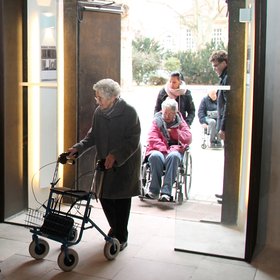 Frau mit Rollator nutzt barrierefreies Portal