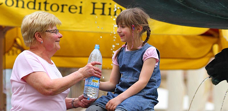 Projekttitelbild: Oma reicht Kind Trinkwasser, © Büro Stadtberatung Fries (P. Steinbacher) 