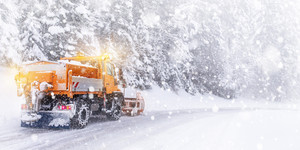 Schneepflug räumt eine verschneite Fahrbahn