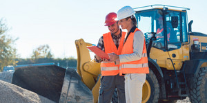 Bauarbeiter und seine Kollegin besprechen einen Arbeitsablauf auf der Baustelle.