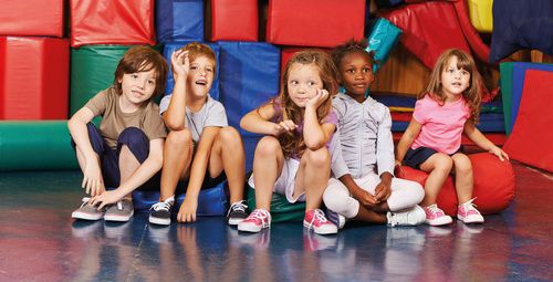 Kinder sitzen auf einer Gymnastikmatte, © Fotolia